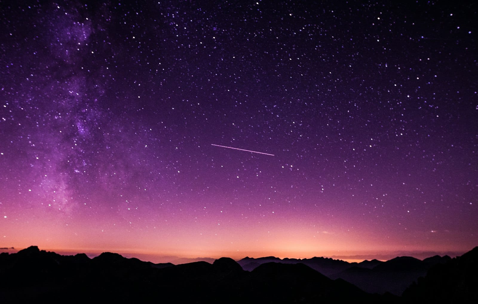 A star-filled night sky above a dark landscape